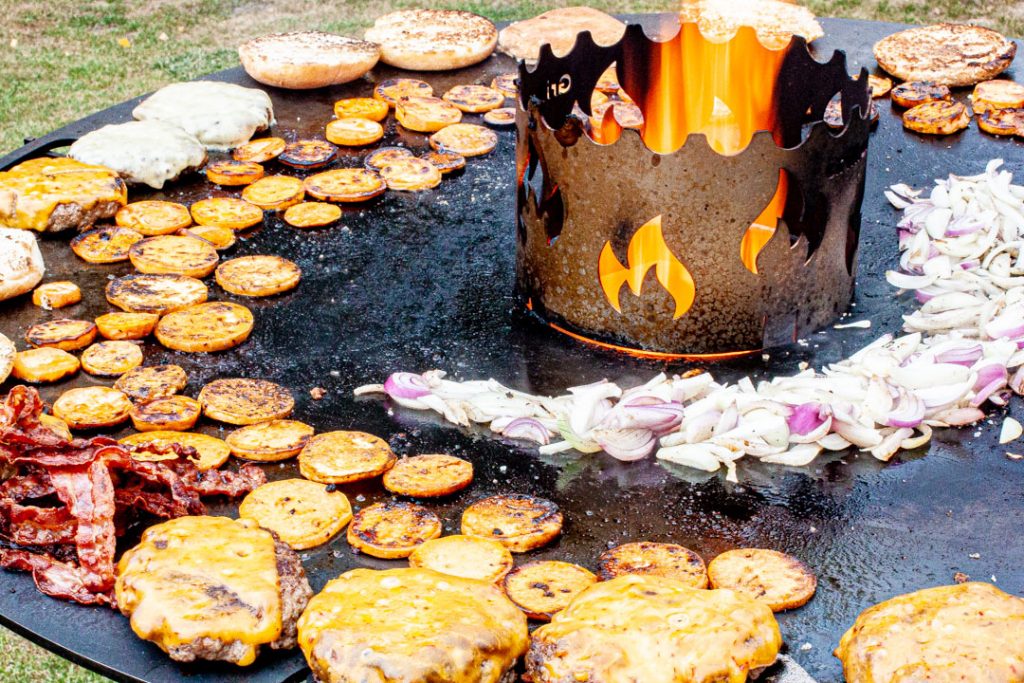 Süßkartoffelchips, Zwiebeln, Bacon und Hamburger auf der Feuerplatte