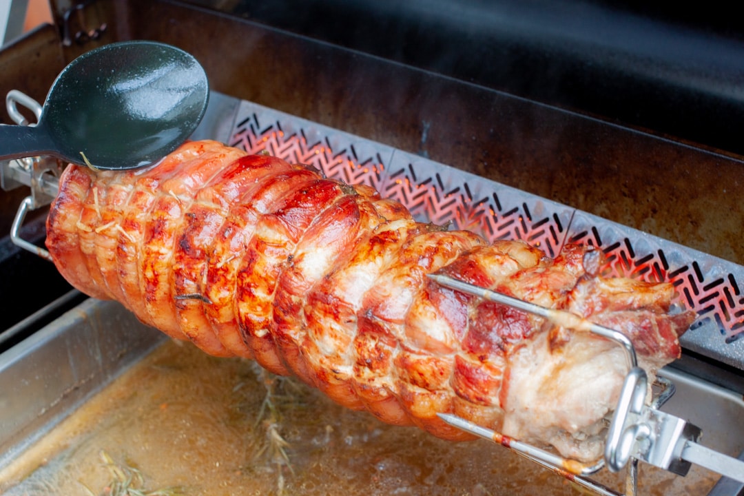 Krustenbraten vom Schweineschinken im Grill auf der Rotisserie