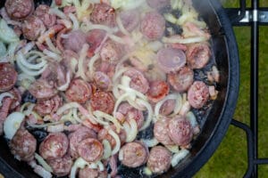 Salsiccia und Zwiebeln mit Deckel des Dutch Oven anbraten
