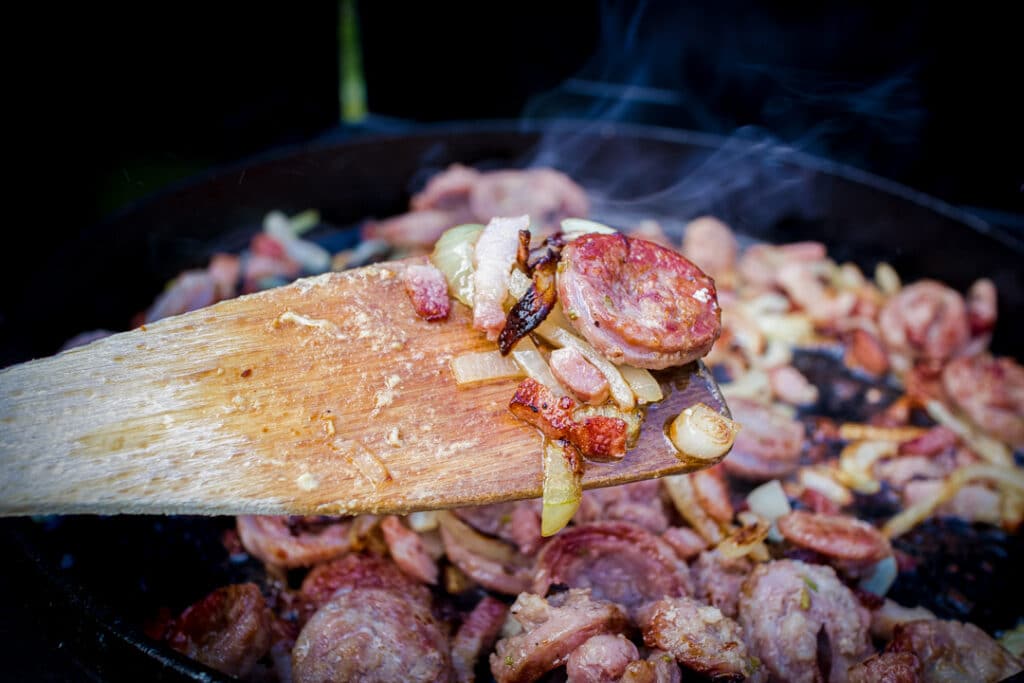 Salsiccia und Zwiebeln mit Deckel des Dutch Oven anbraten